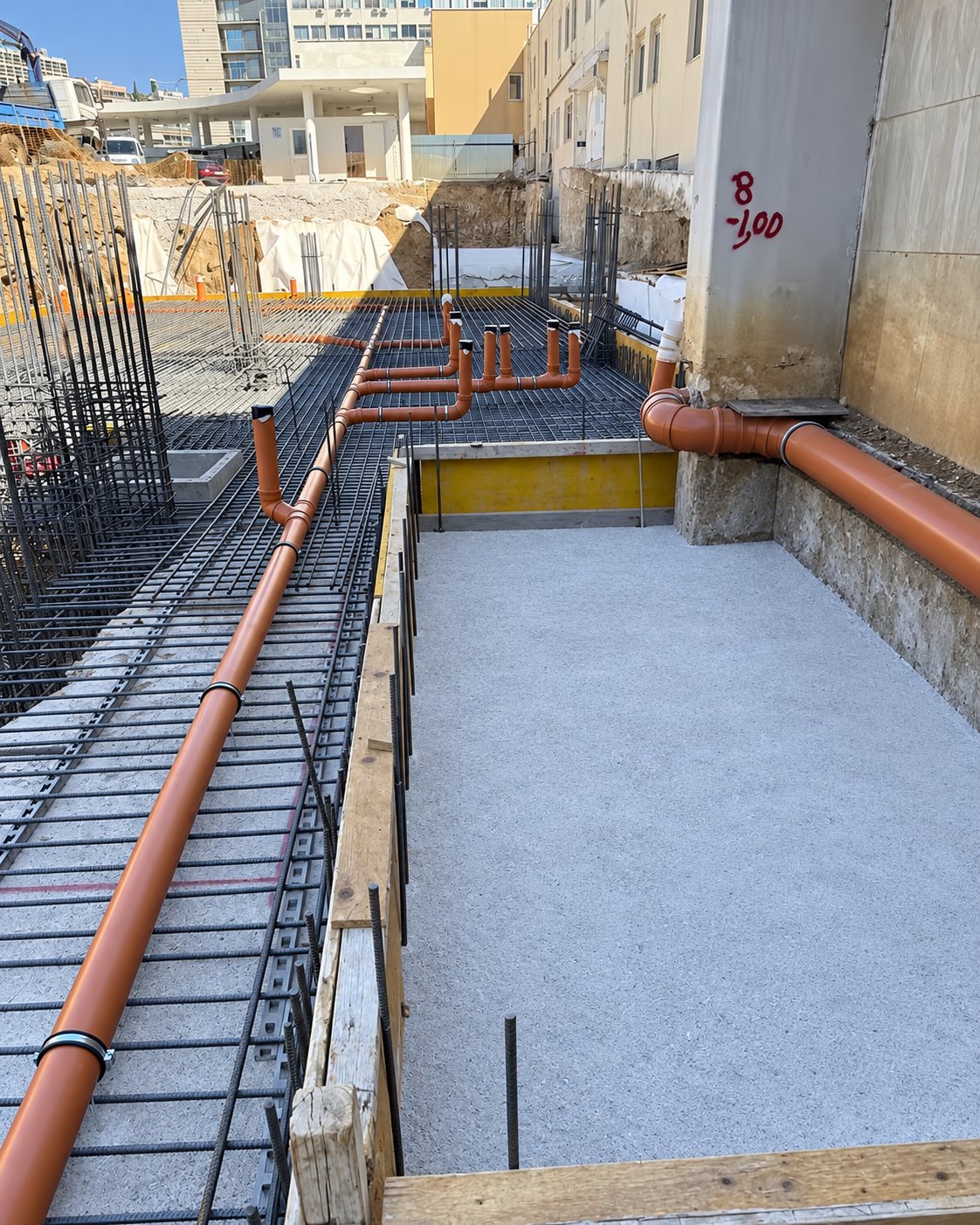Πορτοκαλί σωλήνες επιδάφιου δικτύου πάνω στον οπλισμό, πριν από το σκυρόδεμα.